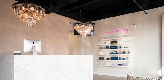 Your Best Face Forward Face Candy's entance lobby. A marble check-out counter stands perpendicular to a marble wall displaying cosmetic items for sale.